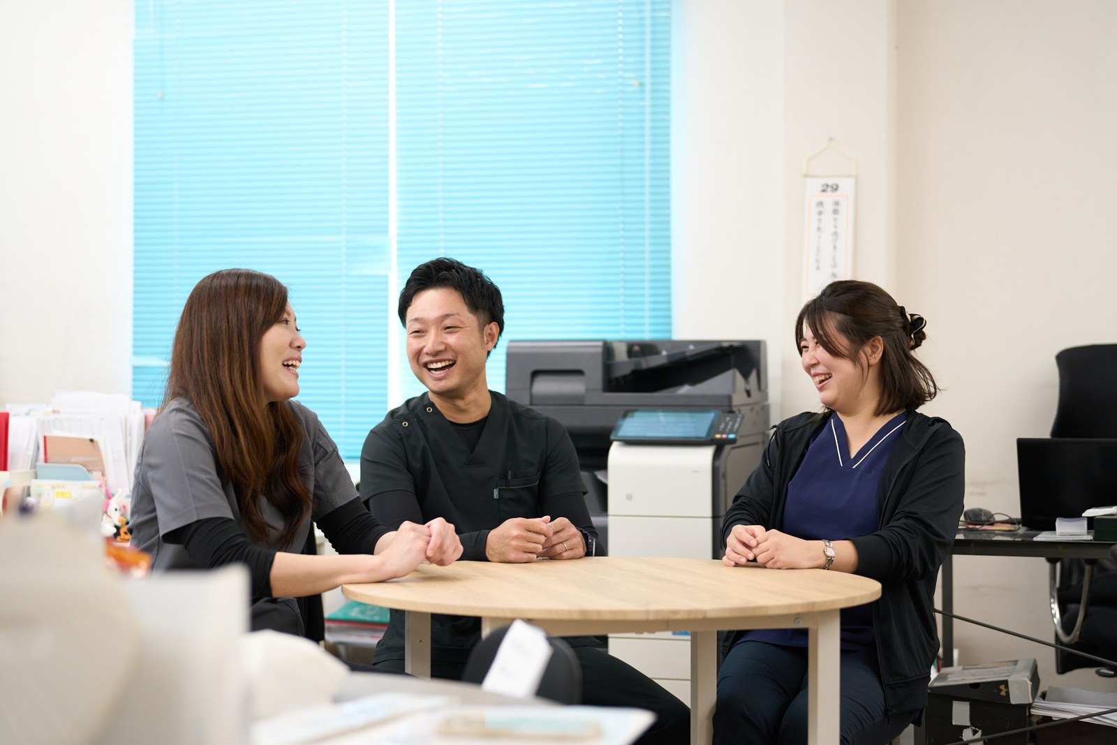 テーブルを囲み、笑顔で会話する系列施設のスタッフ